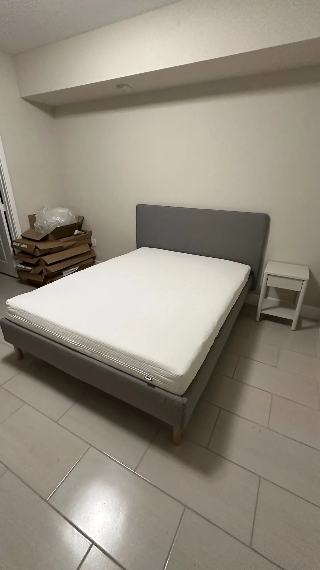 Assembled bed frame with mattress in a bedroom with new flooring