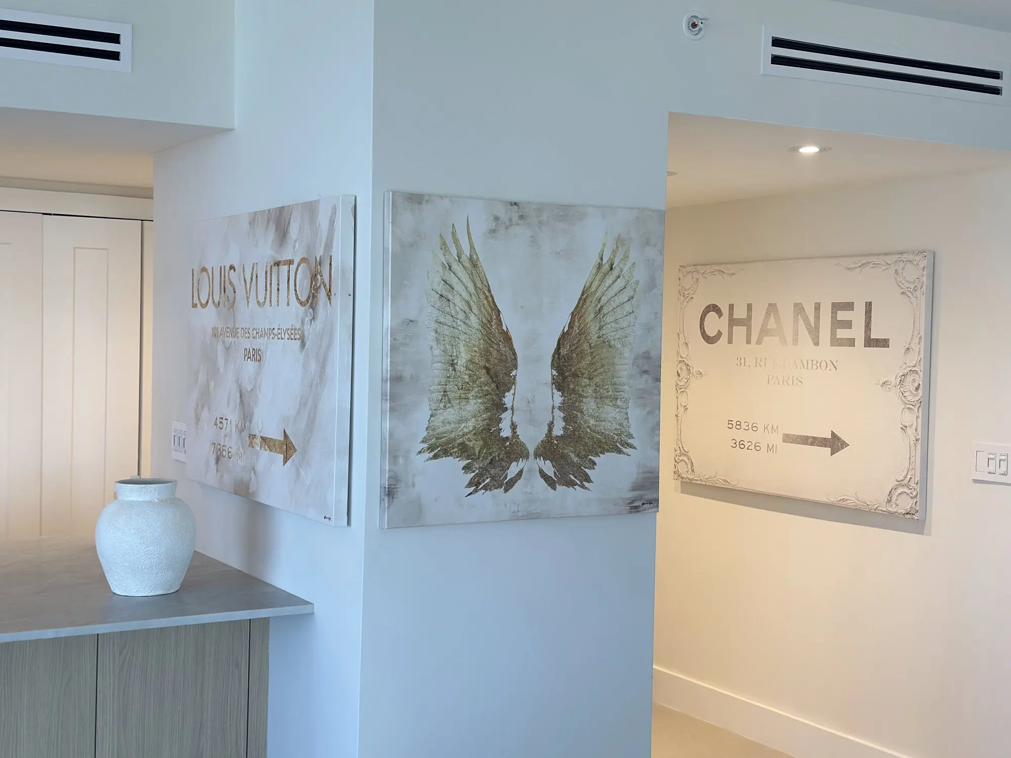 Three large canvas artworks hung in a bright hallway