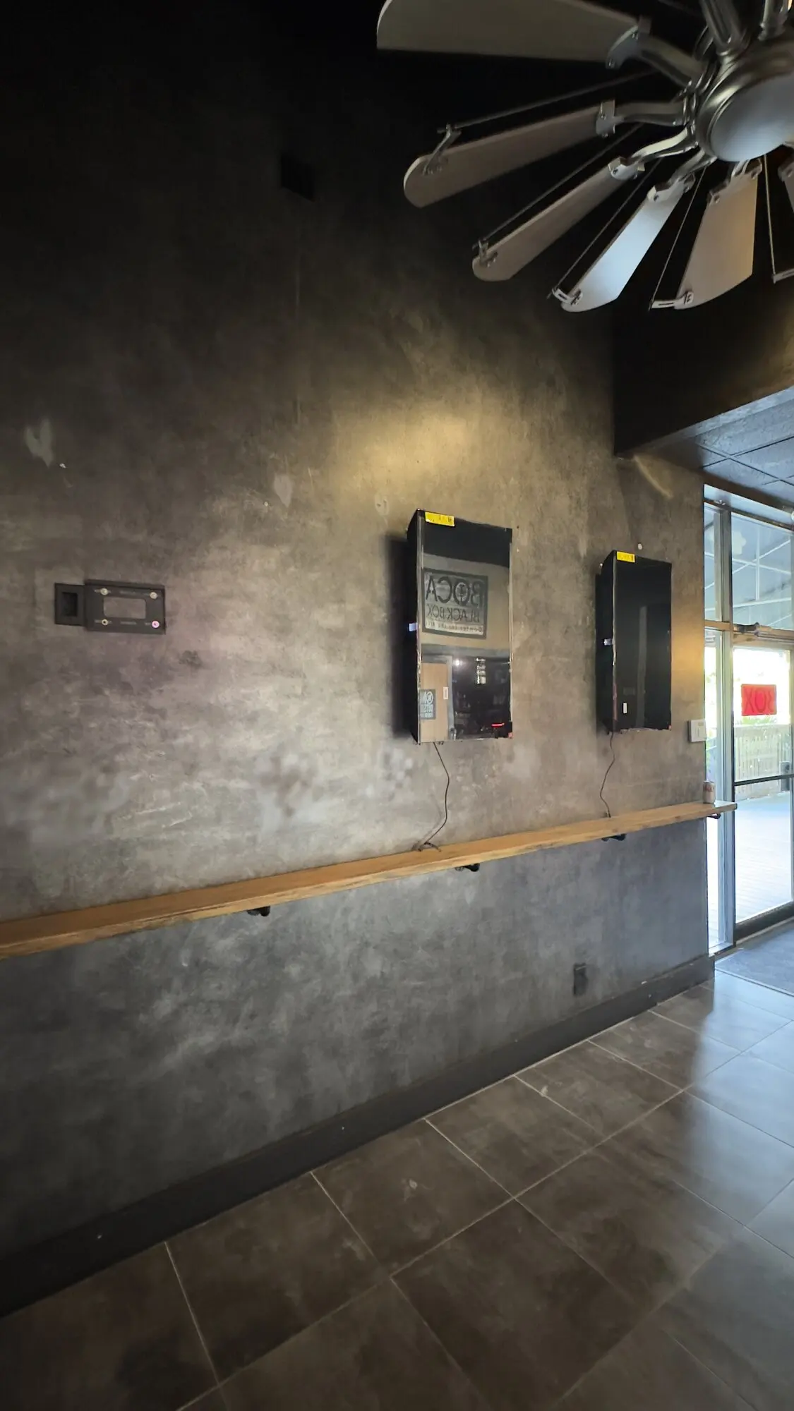 Large ceiling fan and wall-mounted speakers on a polished concrete accent wall