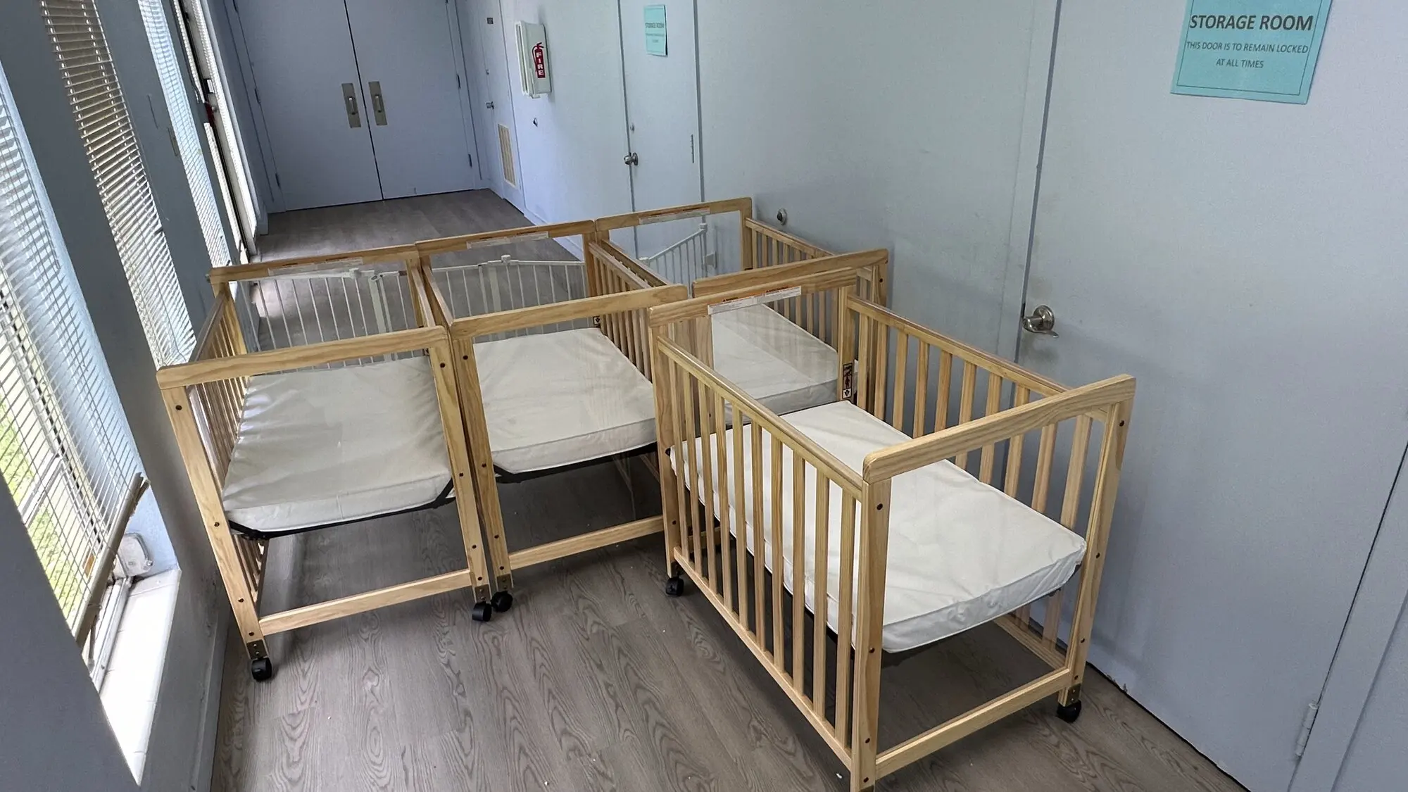 Several wooden cribs assembled in a childcare facility storage room