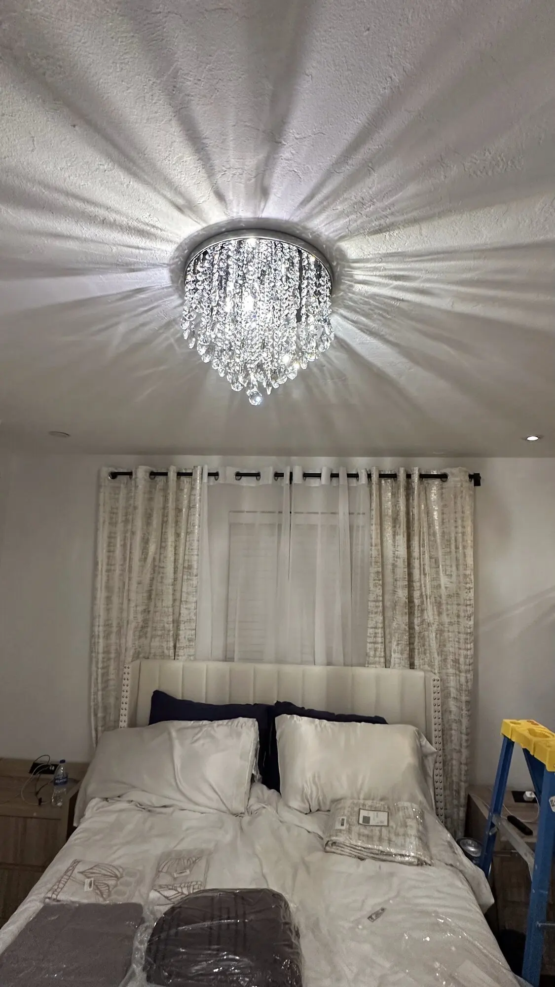 Crystal chandelier installed on a bedroom ceiling casting patterned light