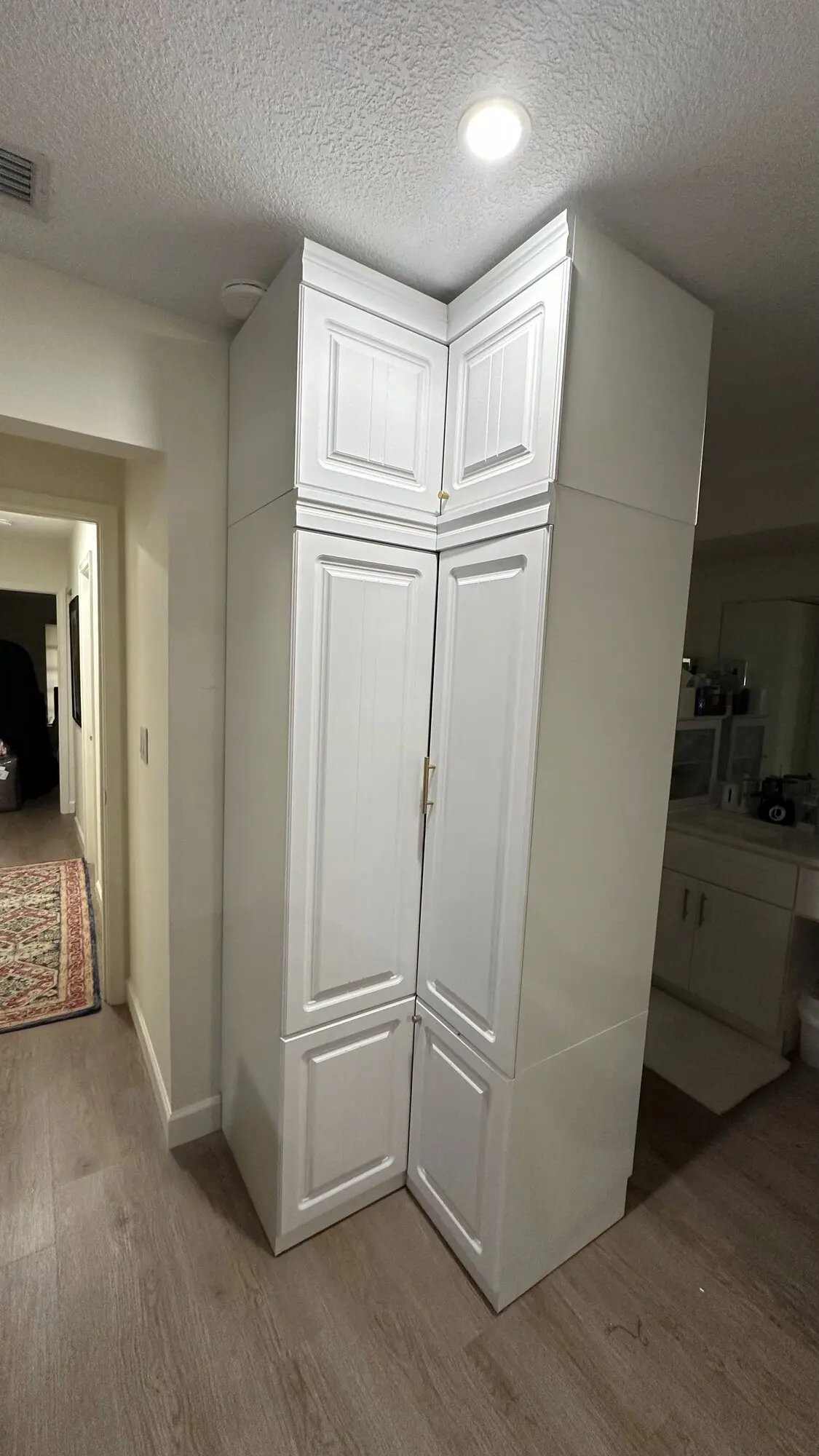 White floor-to-ceiling closet cabinetry installed in a hallway corner