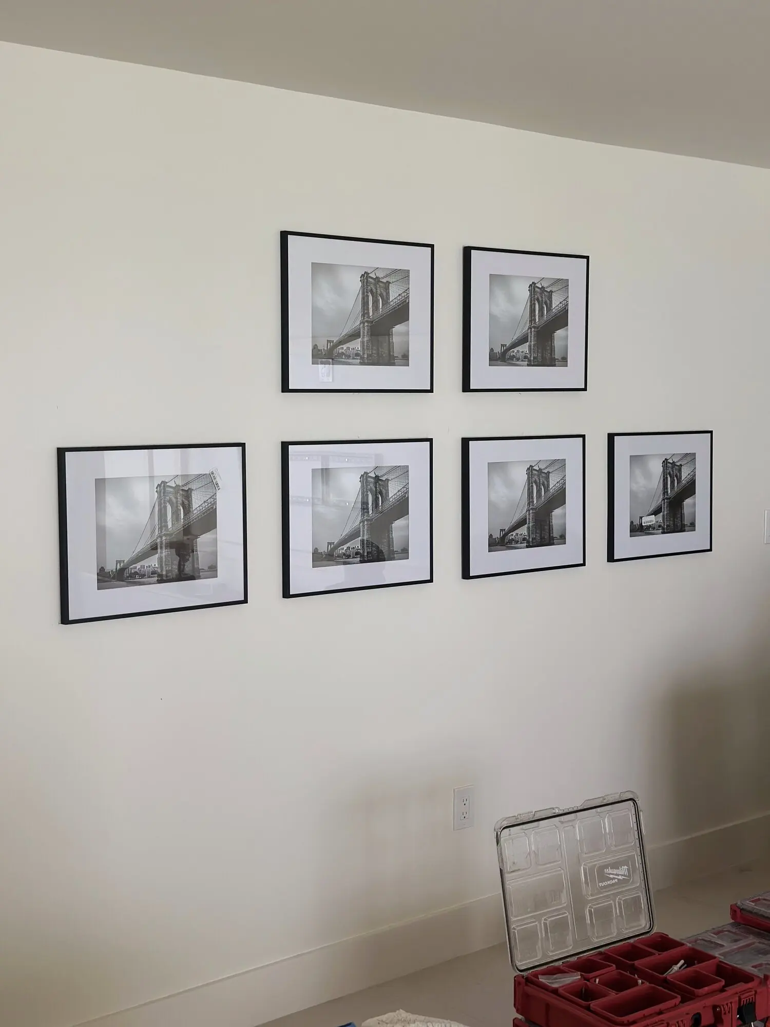 Gallery wall of six black-framed black-and-white photographs aligned on a white wall
