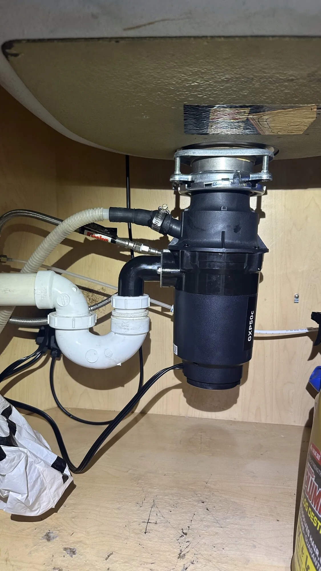 Newly installed garbage disposal unit under a kitchen sink with clean plumbing connections