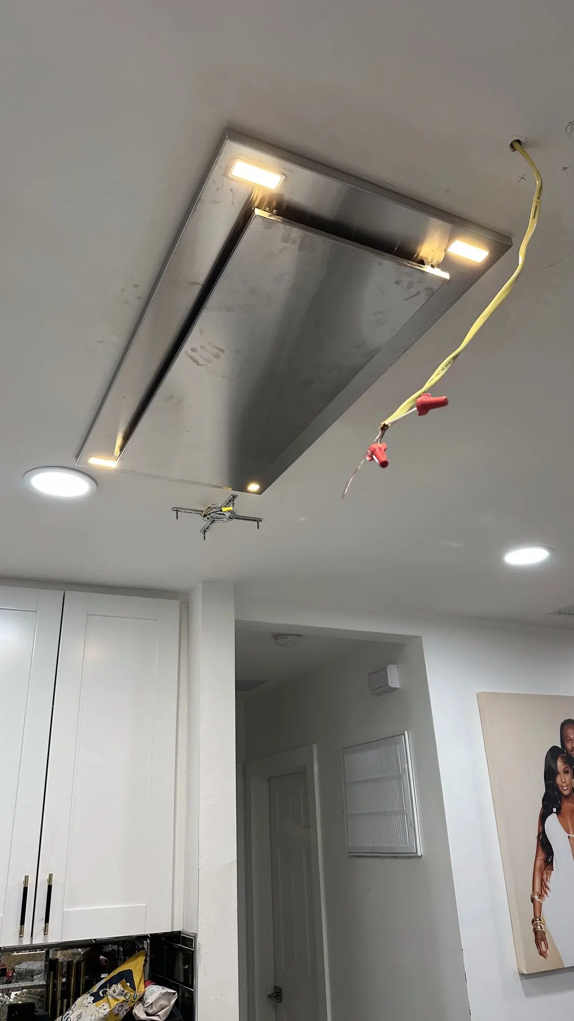 Kitchen range hood partially installed with wiring exposed