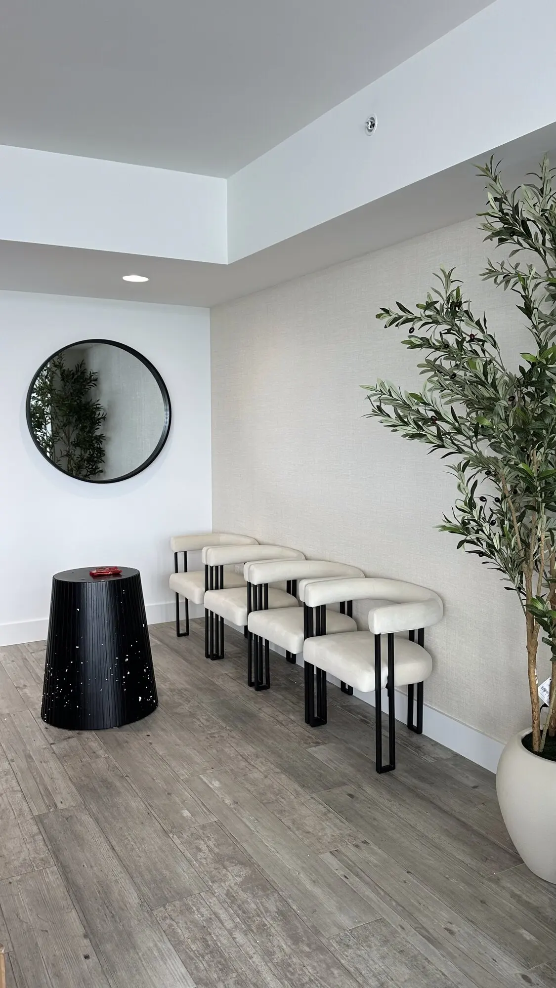 Modern lounge area with a round wall mirror and assembled bar stools