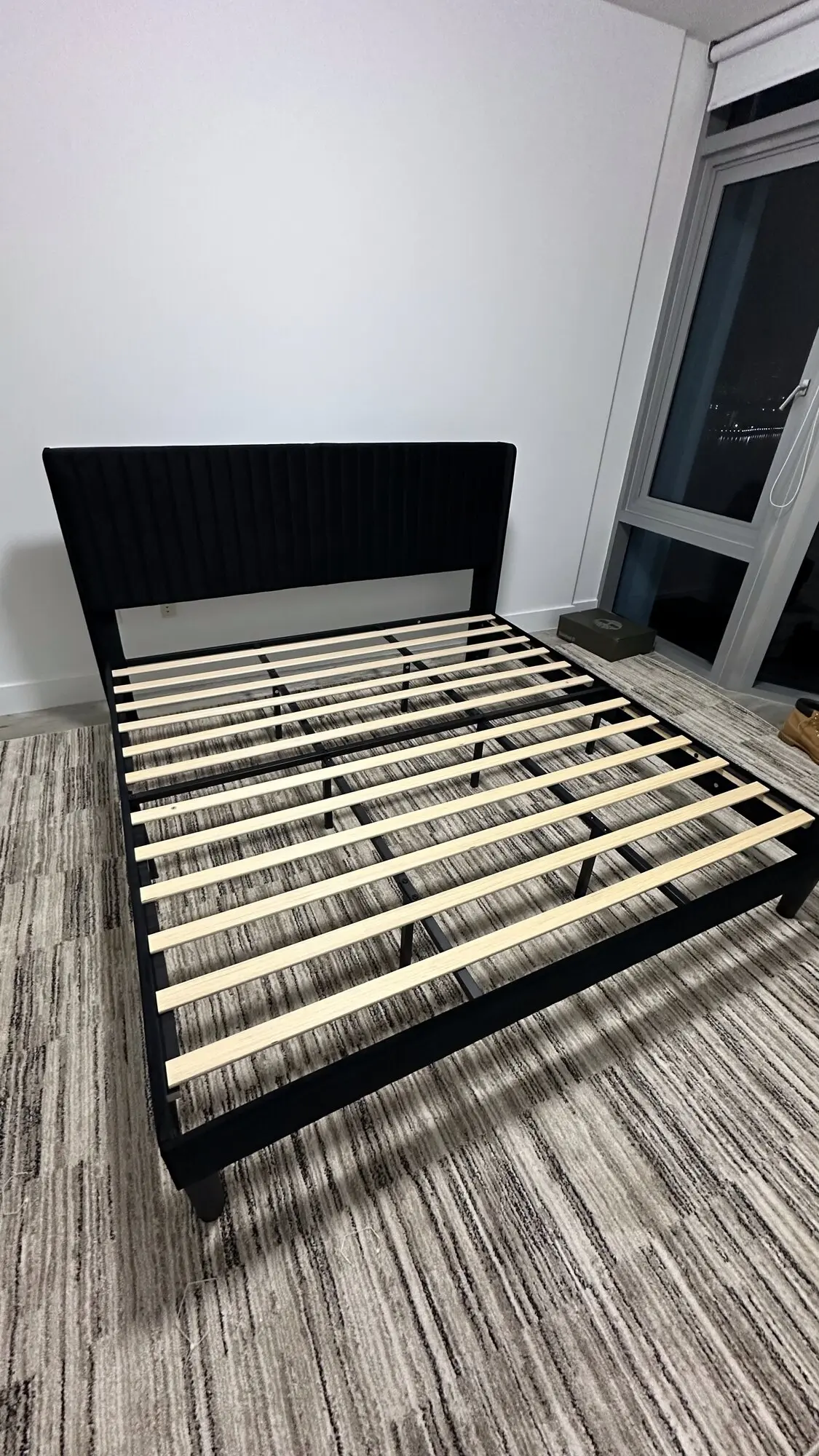 Black upholstered platform bed frame assembled with wooden slats in place