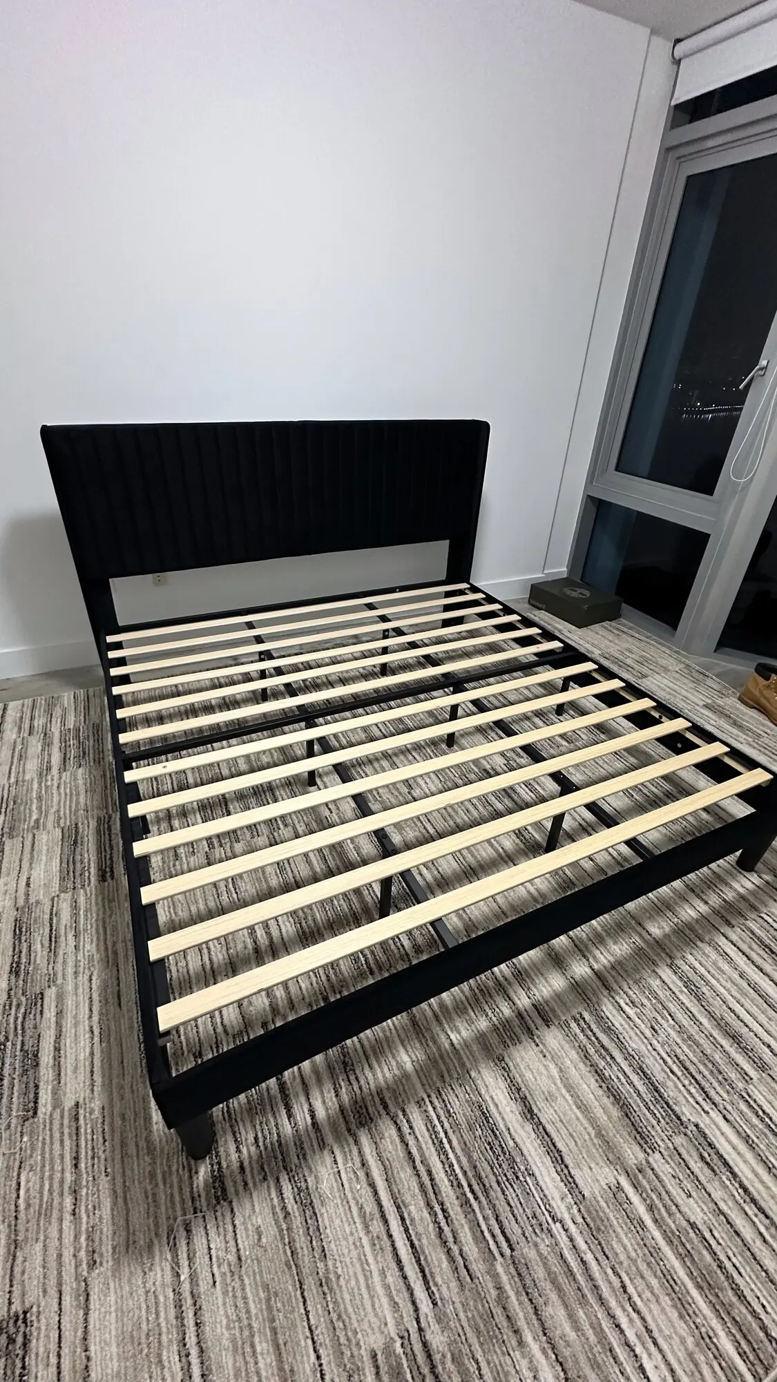 Black upholstered platform bed frame assembled with wooden slats in place