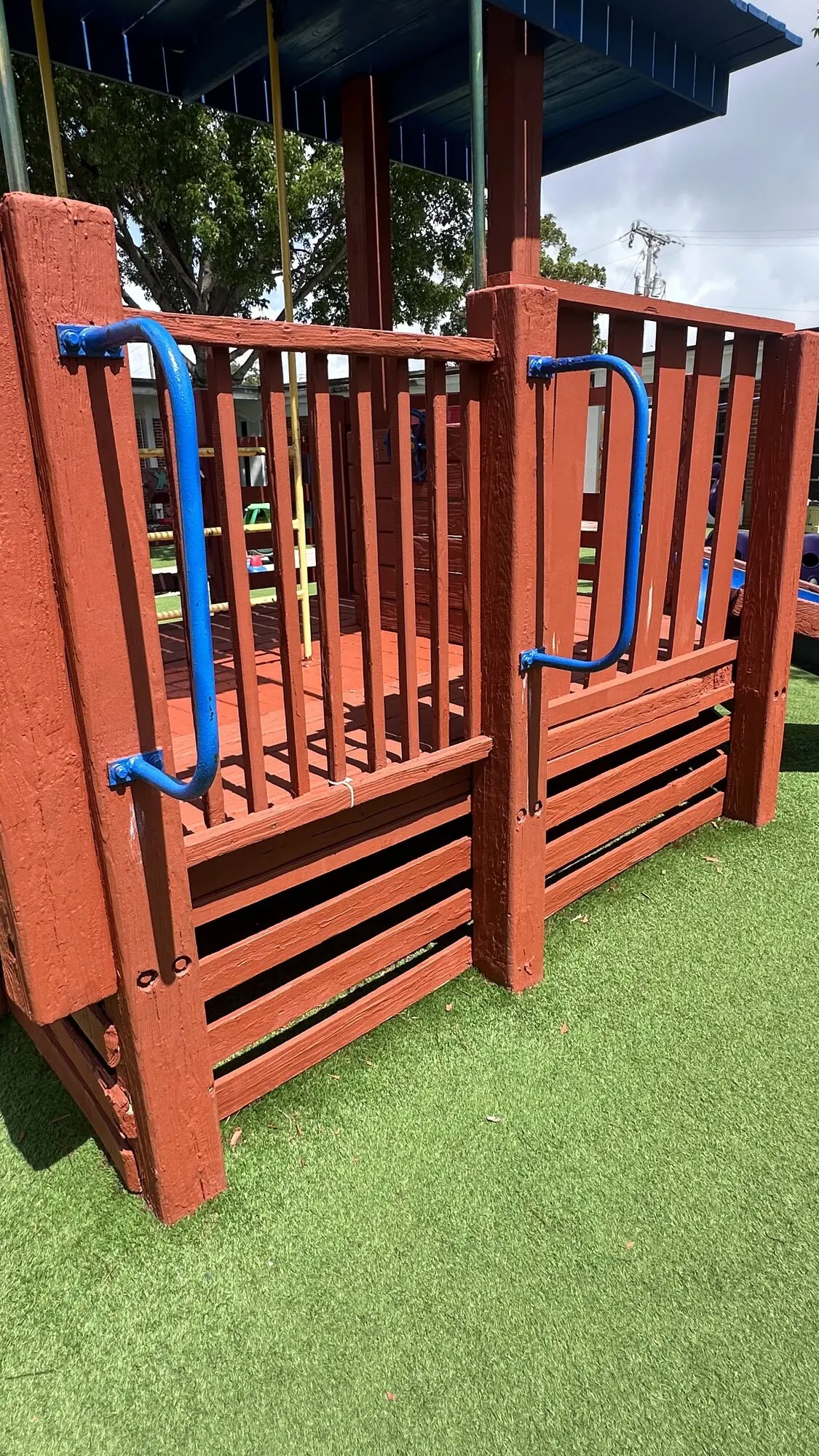 Red and blue playground structure assembled on artificial turf