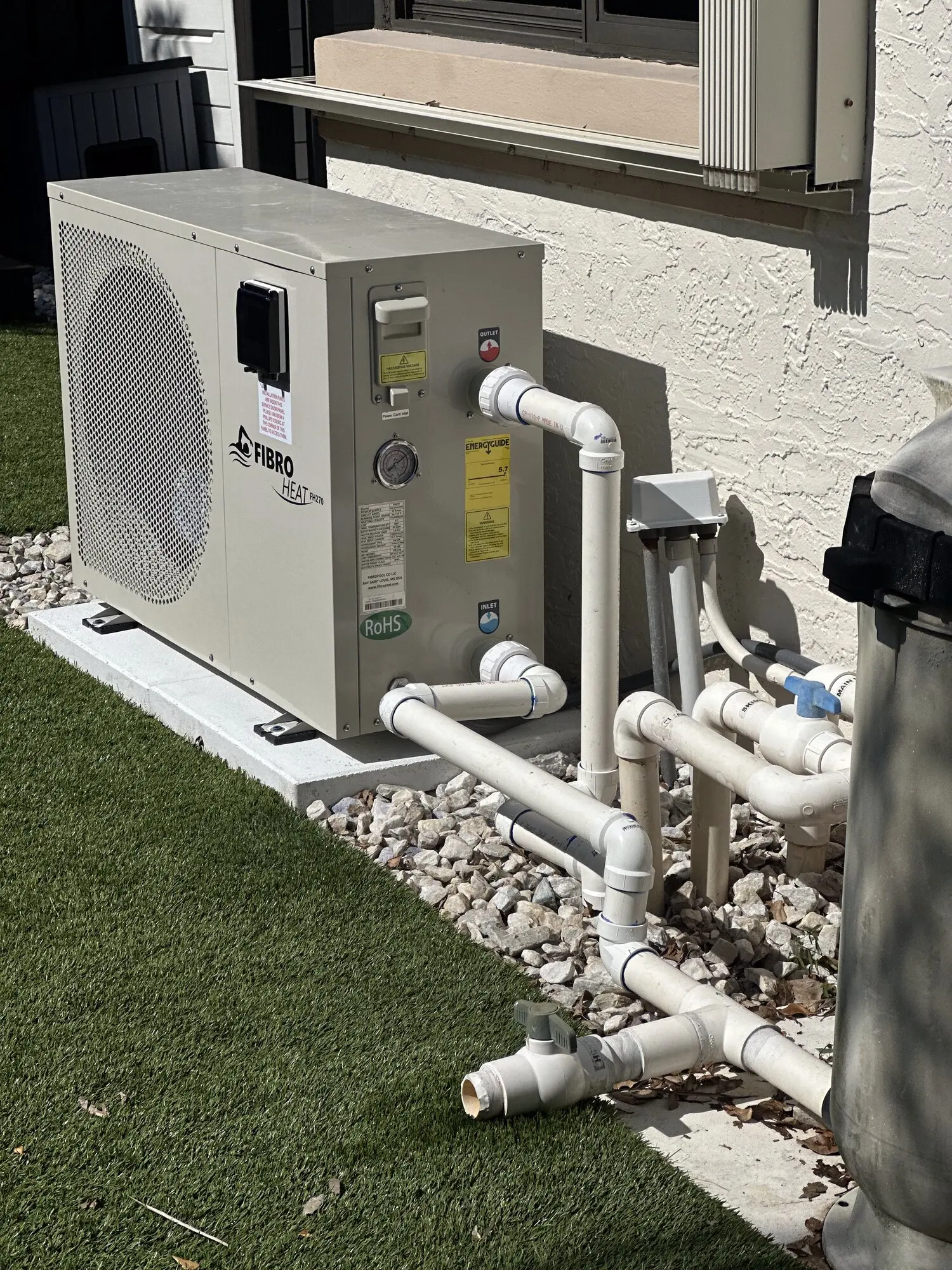 Pool heat pump installed with new PVC plumbing runs on a gravel bed