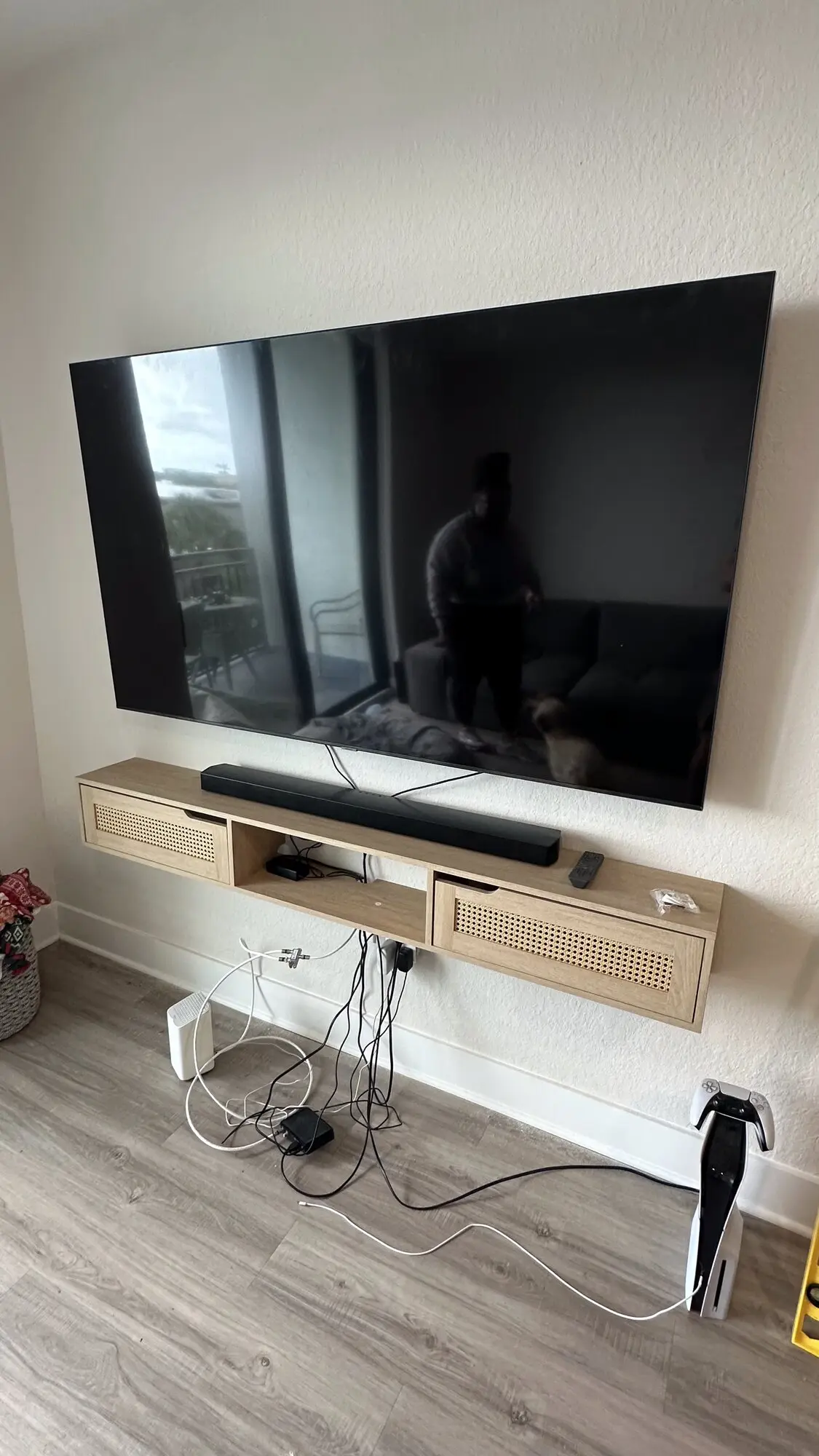 Flat-screen TV mounted on a living room wall above a floating oak console with a soundbar below